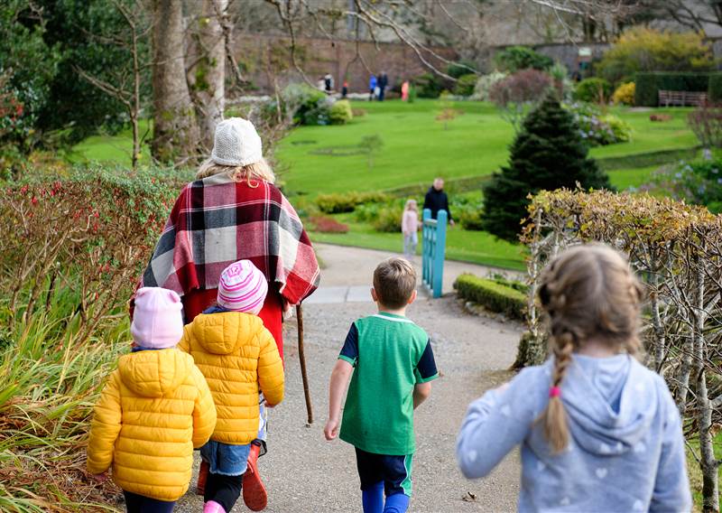 four kids walking on a garden trail with an adult