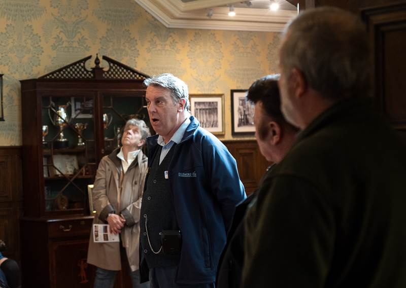 a guide giving a talk to visitors in a victorian styled room