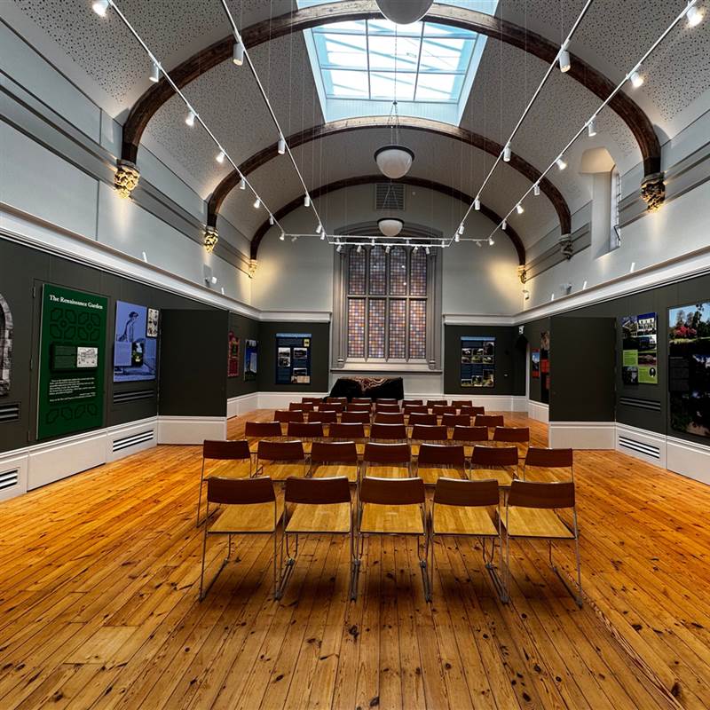 a large hall with rows of wooden chairs and a circular roof 